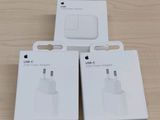 trois boîtes blanches contenant des chargeurs USB Apple posées sur une surface en bois