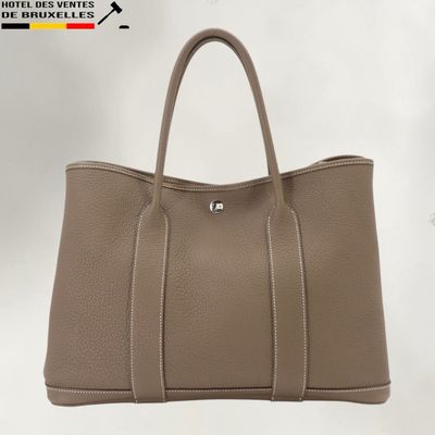 un sac à main en cuir beige muni de deux anses et d'une fermeture à glissière