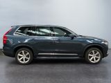 the blue volvo suv is parked in front of a gray wall