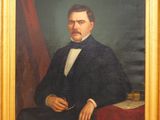 portrait d'un homme en costume noir et nœud papillon, tenant une pipe