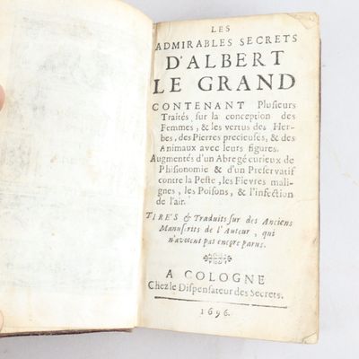 une personne tient un livre ouvert à la main, posé sur une surface blanche