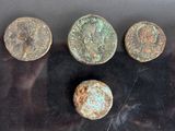 four ancient roman coins sitting on a black surface next to each other
