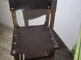a small wooden chair with a leather seat in a room