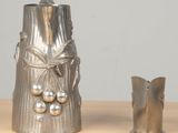 a silver vase sitting next to a silver vase on a table