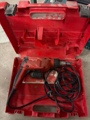 une perceuse électrique dans une boîte à outils rouge, avec son cordon d'alimentation