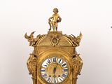 a gold clock sitting on top of a table next to two candles