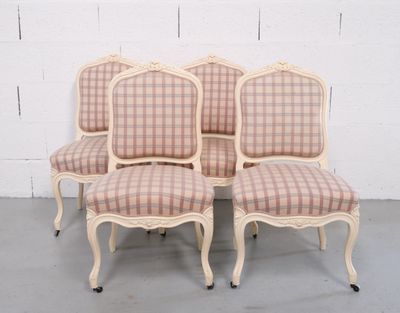 quatre chaises aux assises recouvertes d'un tissu à carreaux, disposées devant un mur de briques blanches