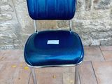 a blue chair that is sitting in front of a stone wall