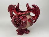 a red vase with a dragon and rose decoration on it