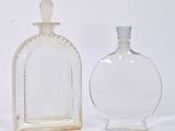 two glass bottles sitting next to each other on a white surface