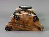 a small clock sitting on top of a piece of wood