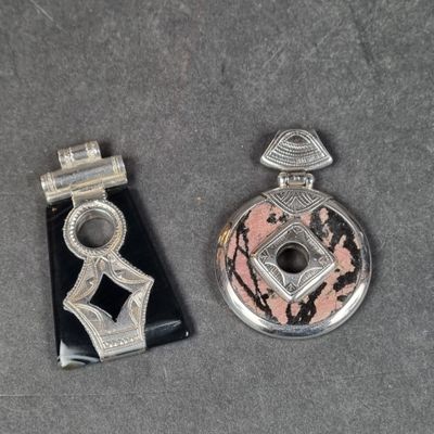 deux bijoux argentés et noirs posés sur une surface grise