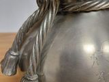 a silver vase with a rope wrapped around it on a table