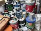 several buckets of paint are stacked on top of each other in a room