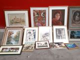 a lot of framed pictures on the floor next to a red wall