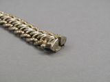 a close up of a silver bracelet on a gray surface