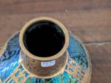 a blue and gold vase sitting on a wooden table