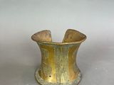 pair of brass cuff bracelets with decorative designs on a grey background