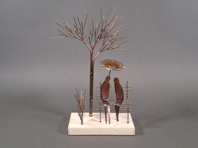 a sculpture of two people sitting on a bench under an umbrella