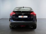 the rear end of a black car in a room with a white wall