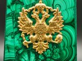 a close up of a green and gold pendant on a black background