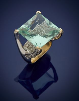 a gold ring with an emerald stone on a blue background