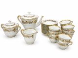 a white and gold tea set with cups and saucers