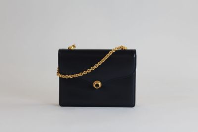 un sac à main noir auquel est suspendue une chaîne dorée