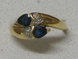 an image of a gold ring with two blue sapphires and diamonds
