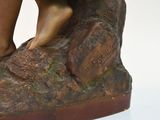a bronze statue of a person standing on a rock