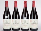 trois bouteilles de vin rouge sont alignées sur une surface blanche