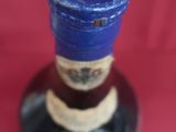 a bottle of liquor sitting on a saucer with a cigarette