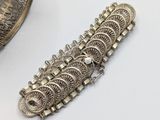 silver plated bracelet with intricate design on a white surface