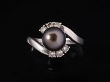 une bague en perle noire et diamants sur fond noir