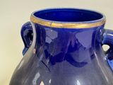 a blue vase sitting on a table with a gold rim