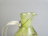 a green glass pitcher with a floral design on it