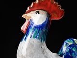 a close up of a ceramic rooster on a black background