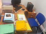 un bureau sur lequel se trouvent un ordinateur, un écran et plusieurs dossiers