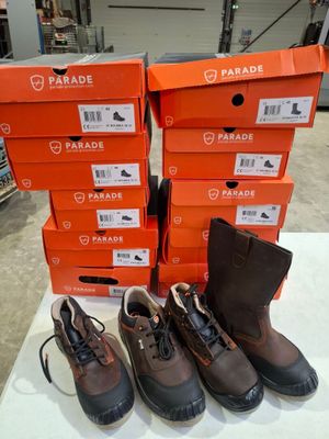 quatre paires de chaussures sont alignées sur une table devant des cartons orange