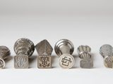a group of silver metal stamping tools sitting on top of a white surface
