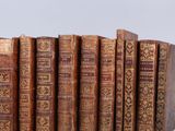 several old books are lined up in a row on a white surface