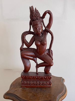 une photo représentant une statue d'une femme assise sur une table en bois