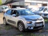 une petite voiture argentée garée devant un immeuble