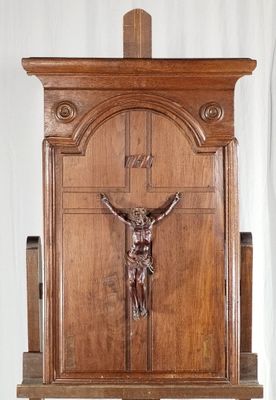 une statue de Jésus sur la croix, posée sur un socle en bois