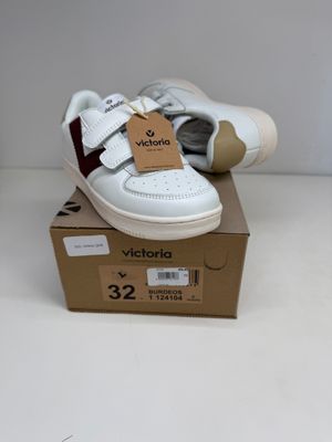 des chaussures de bébé blanches et rouges posées sur une boîte, sur une surface blanche