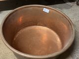 a large metal bowl sitting on the floor next to a wooden cabinet