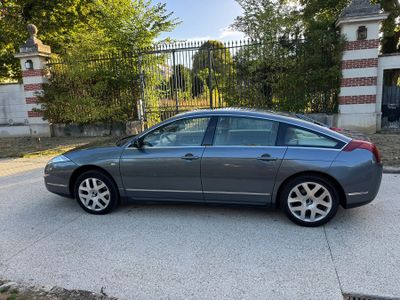 La voiture est garée sur le bord de la route, devant une clôture.