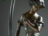 bronze statue of a woman holding a flower next to a lamp