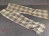 un pantalon à carreaux pour homme posé sur un canapé, sur fond bleu