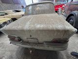 a dirty car parked in a garage with other cars in the background